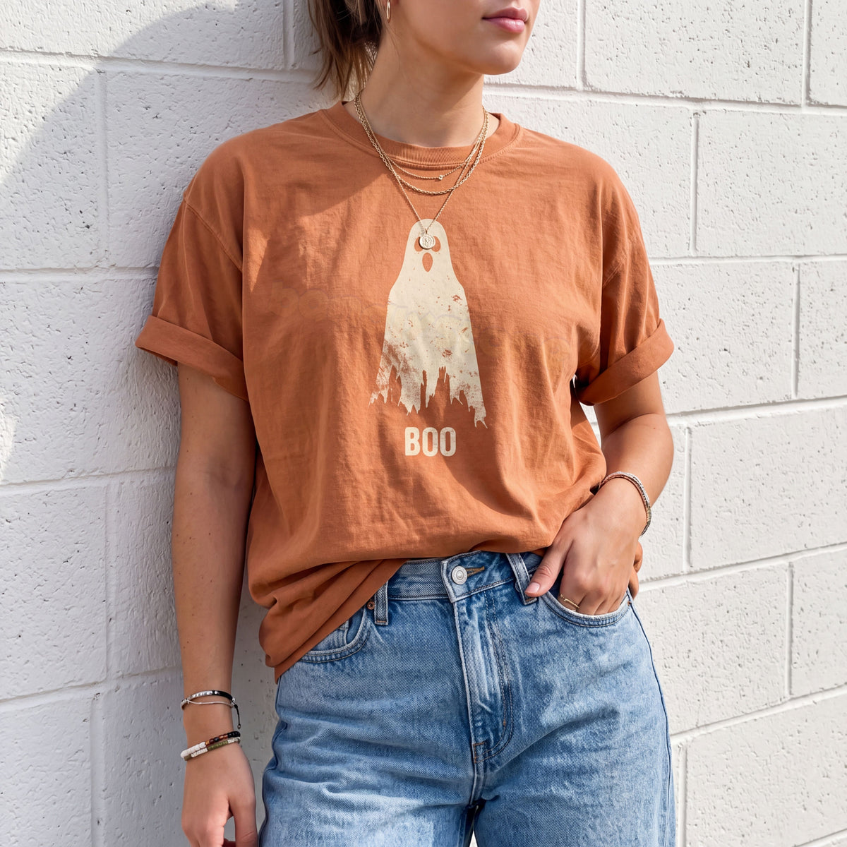 Grungy Ghost T-Shirt in Yam, worn by a person leaning on a white brick wall, ghost graphic and BOO text on front.