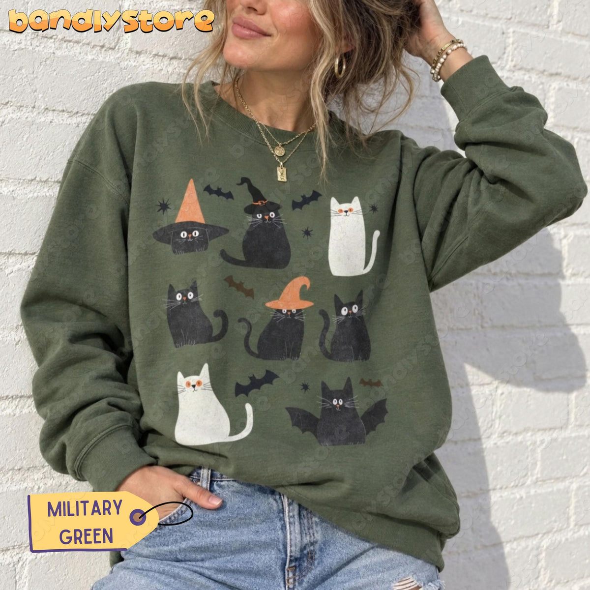 Cute Halloween Black Cat Sweatshirt in military green worn front-facing against a white brick wall.