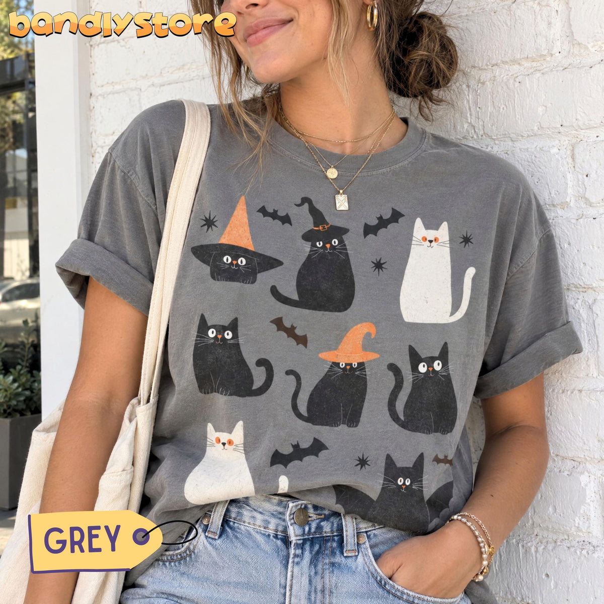 Cute Halloween Black Cats T-Shirt in grey worn by a woman against a white brick wall.