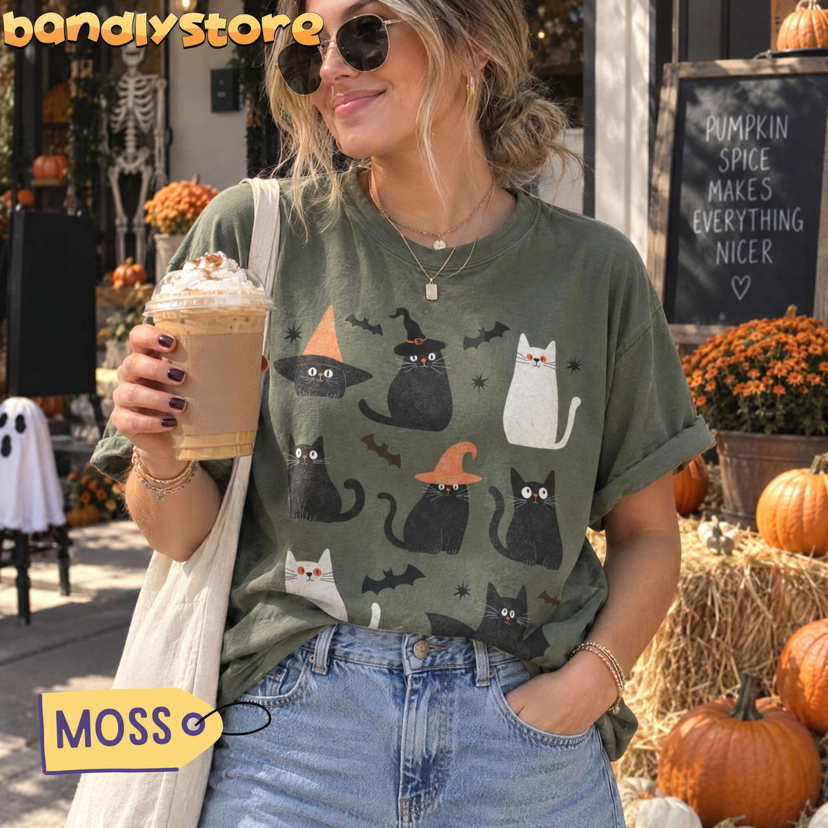 Cute Halloween Black Cats T-Shirt in moss on a woman outdoors holding a drink among pumpkins and hay.