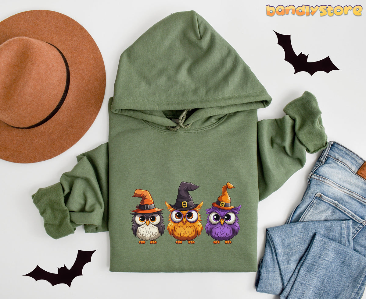 Halloween Owl Hoodie in military green flat-laid with brown hat, jeans and bats nearby.