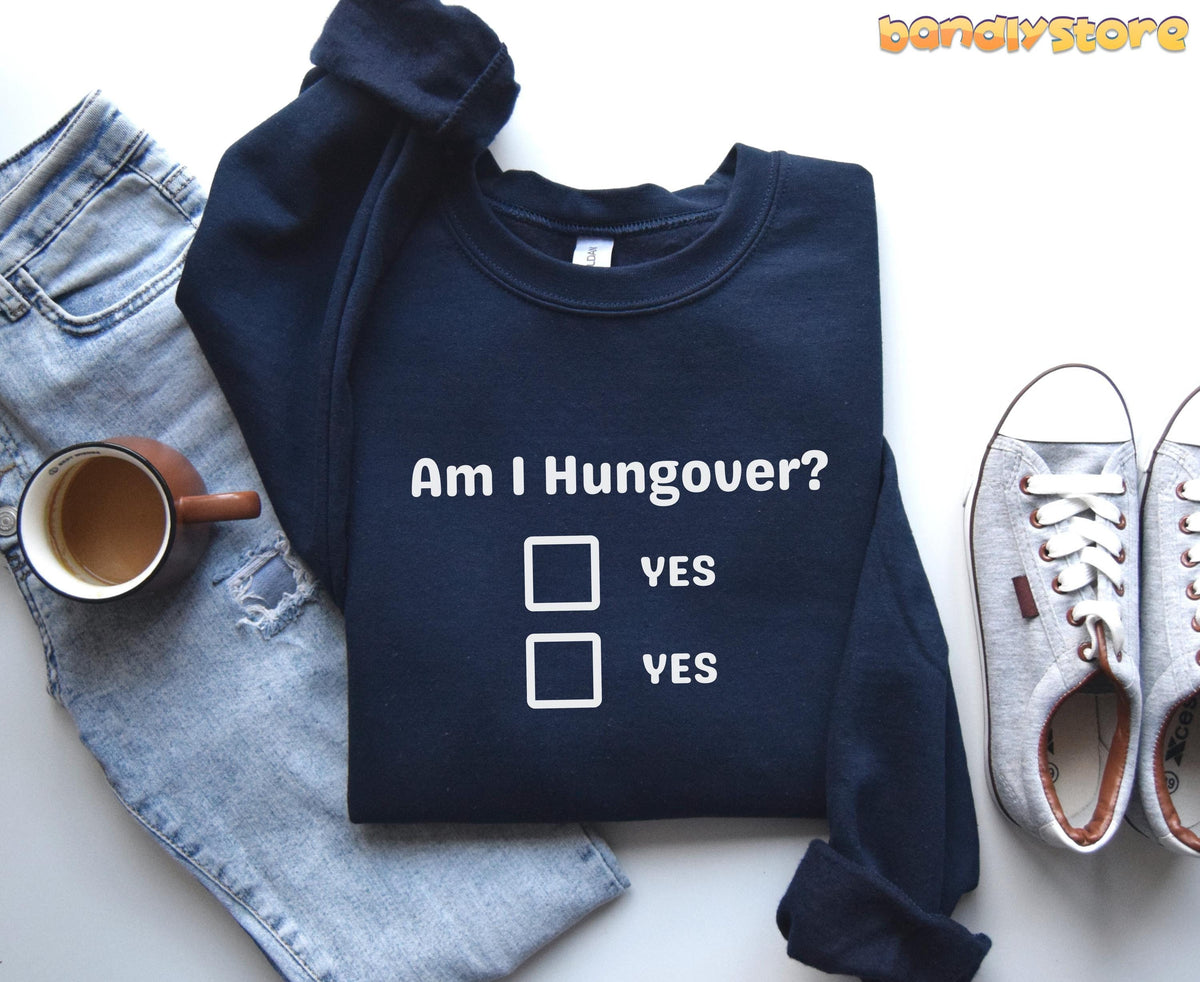 Hangover Sweatshirt in navy, folded flat beside ripped jeans, a coffee mug and grey sneakers on white.