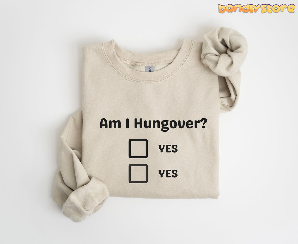 Hangover Sweatshirt in sand, folded flat on white with sleeves crossed, showing dual YES checkboxes.