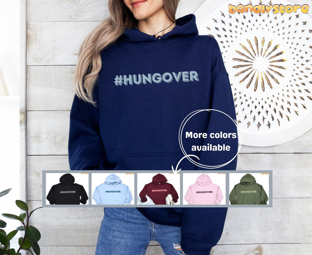 Hashtag Hangover Hoodie in navy worn front-facing against a pale wood wall beside a plant and round wall art.
