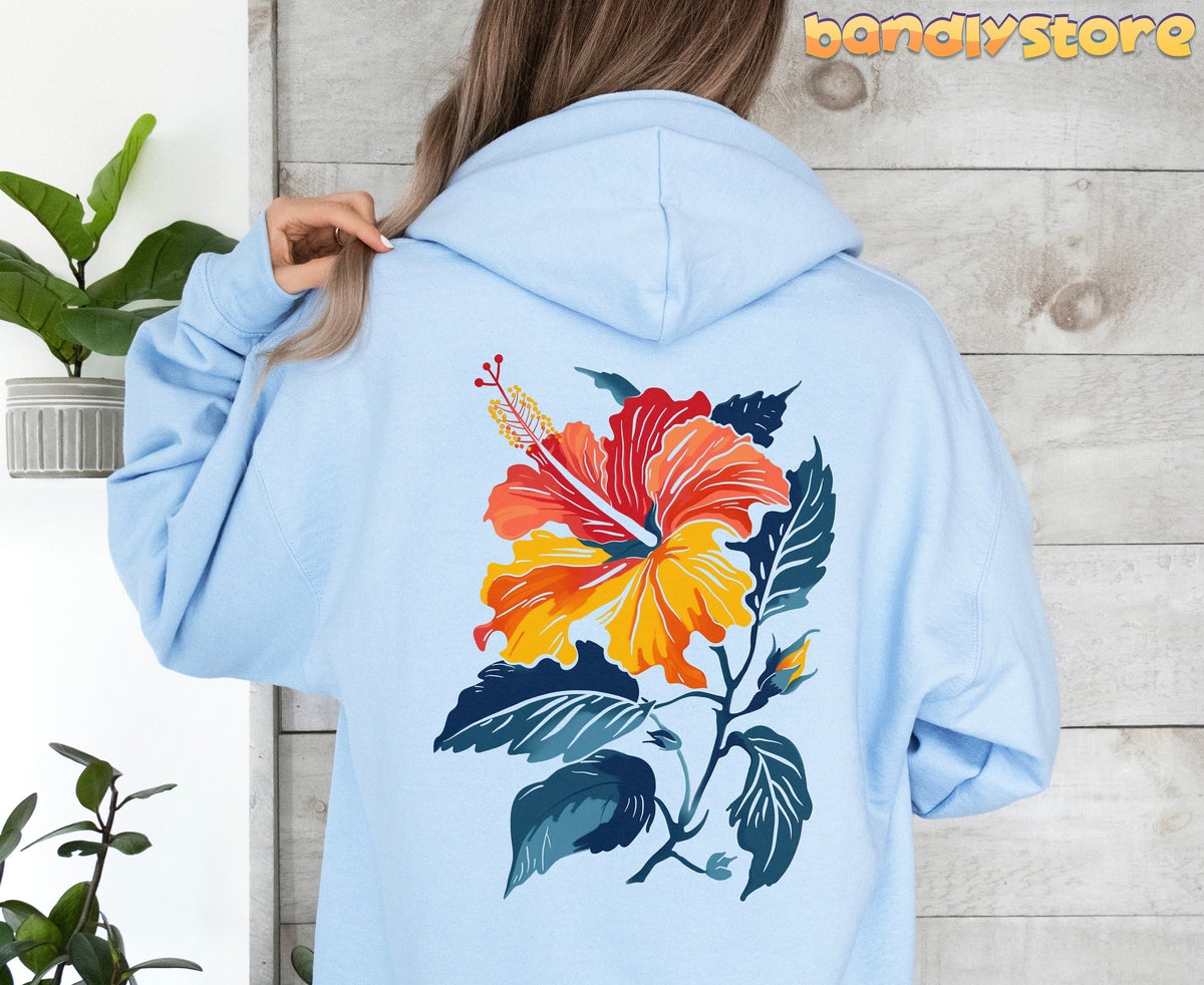 Hibiscus Flower Hoodie in light blue, rear view on a person against wood paneling with plants nearby.