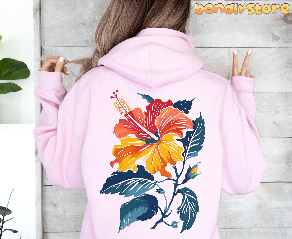 Hibiscus Flower Hoodie in light pink, back view against wood wall with plants, large floral print and peace-sign hand.