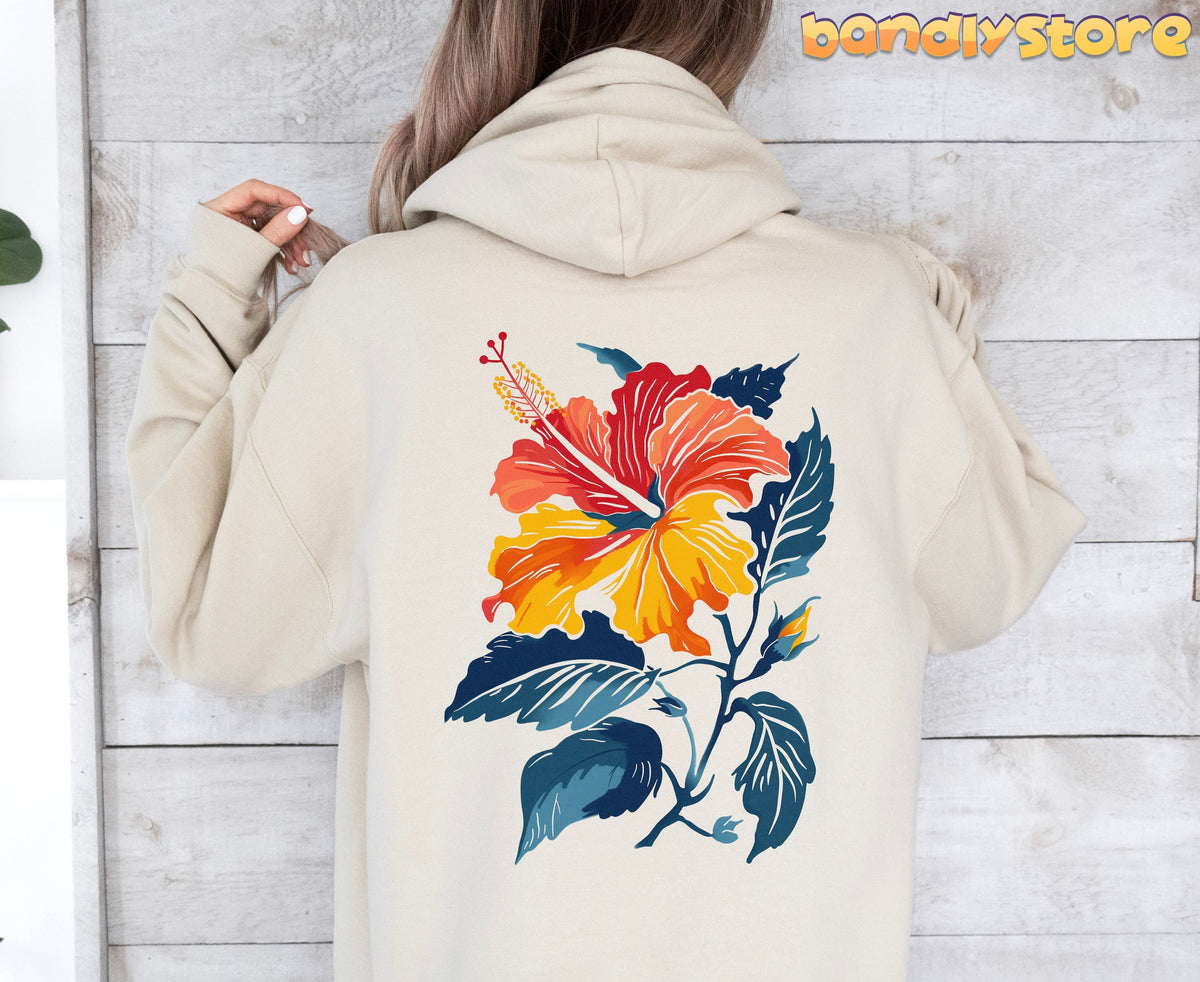 Hibiscus Flower Hoodie in sand, back view on a person against a white wooden wall.