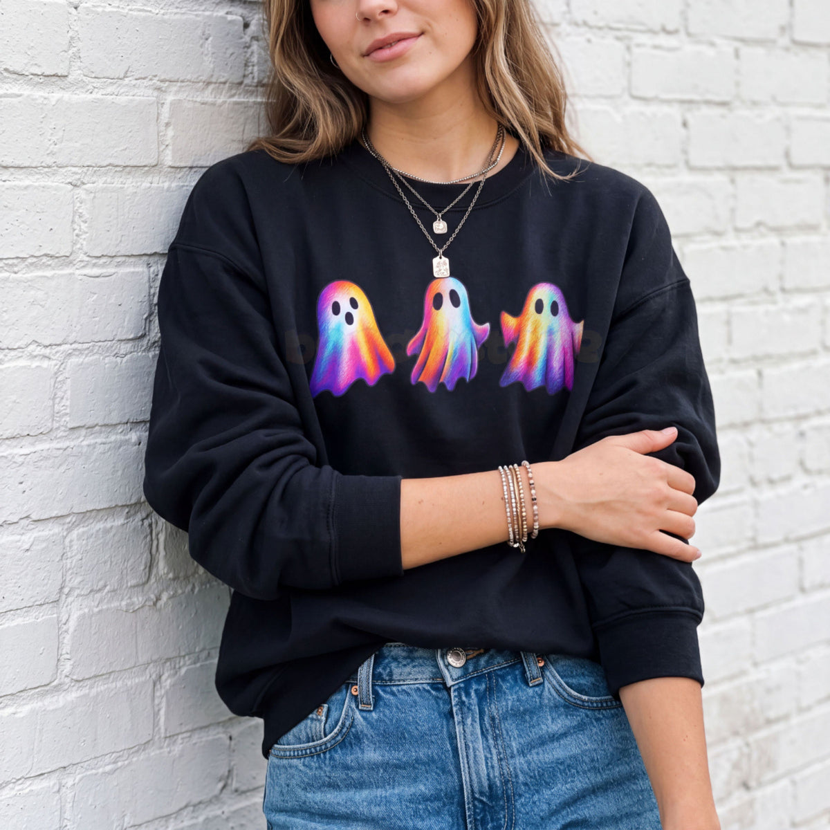 Iridescent Ghosts Sweatshirt in black on a model leaning against a white brick wall, arms crossed.