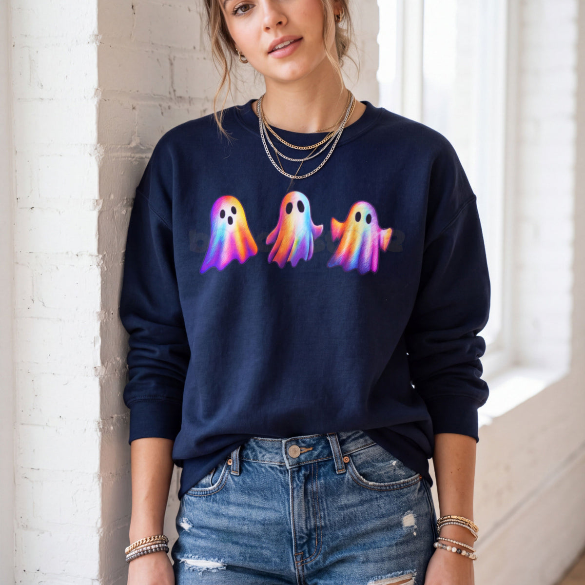 Iridescent Ghosts Sweatshirt in navy on a model leaning against a white brick wall by a window.