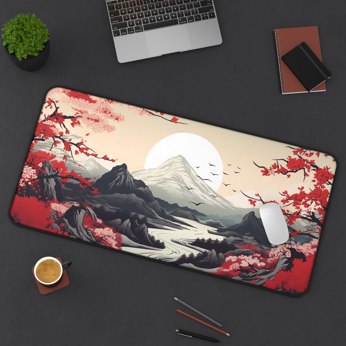 Japanese Mountains Desk Mat 16 × 32 inches on dark desk from above with laptop, plant, notebooks, mouse, coffee and pencils.