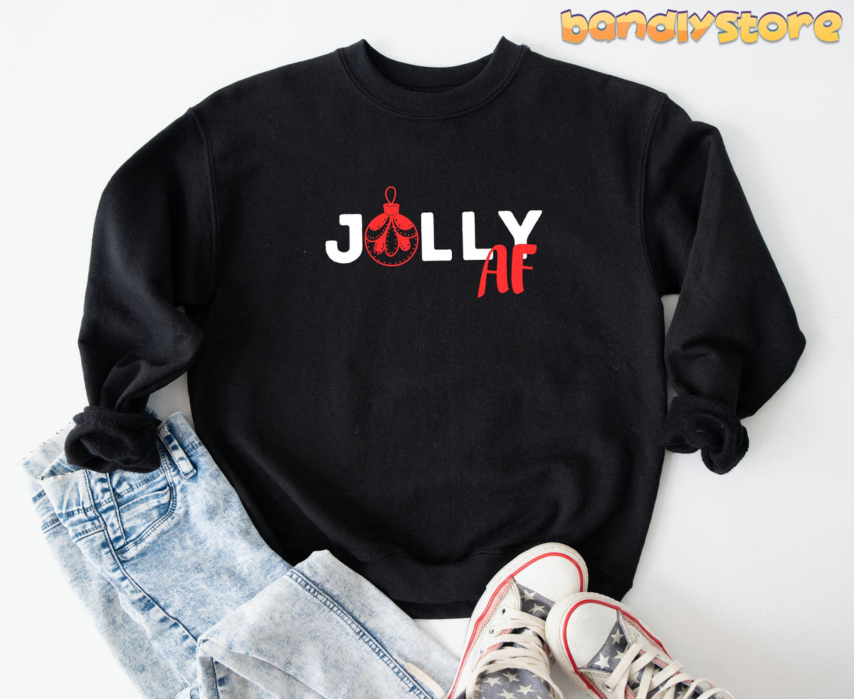Jolly AF Christmas Sweatshirt in black, flat-laid with jeans and star-print sneakers nearby.