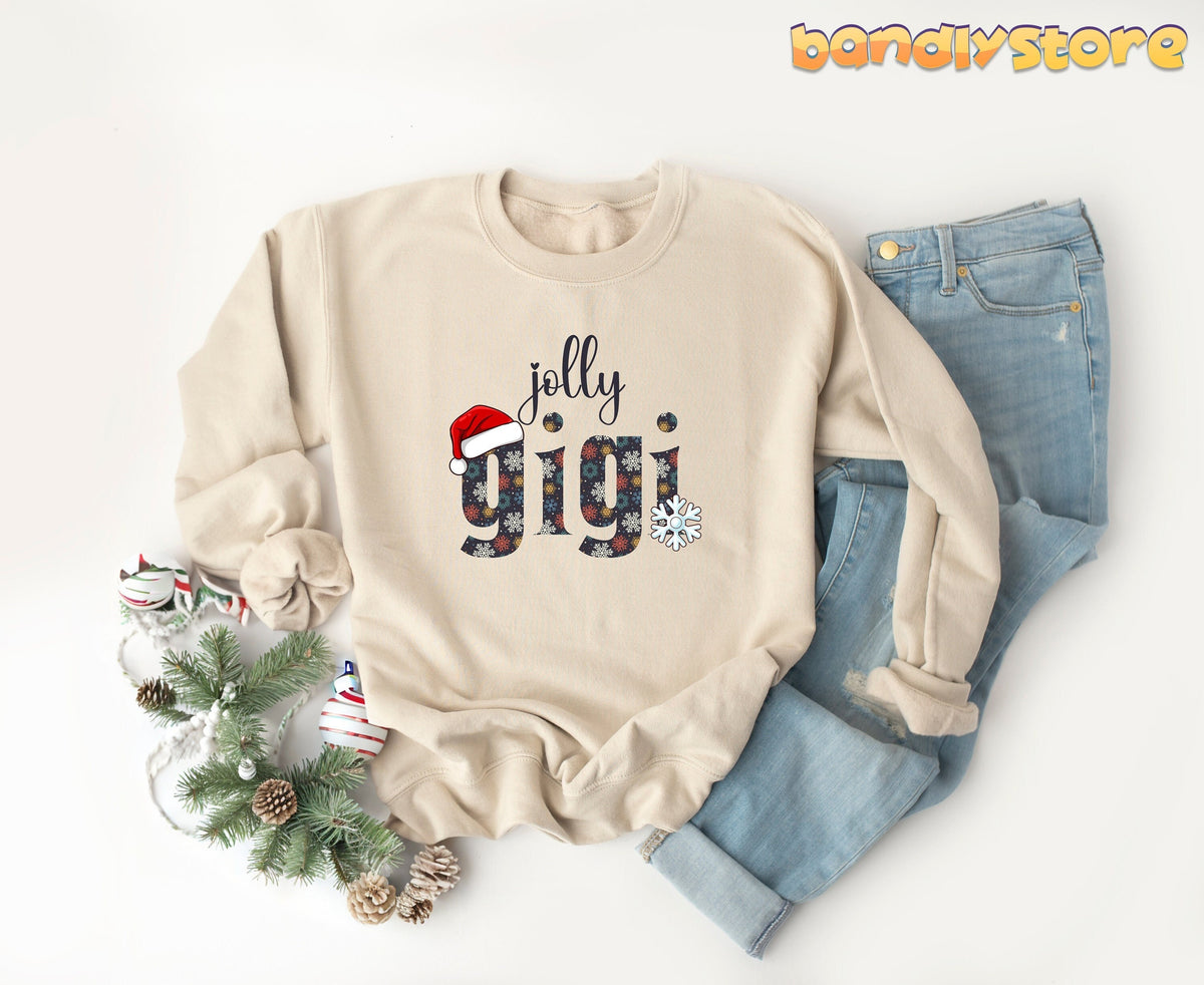 Jolly Gigi Sweatshirt in sand laid flat beside jeans with pine branches, ornaments and pinecones.