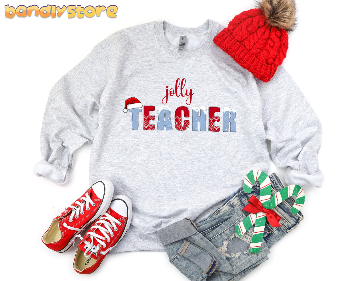 Jolly Teacher Sweatshirt in ash laid flat beside red beanie, sneakers, jeans and candy canes.