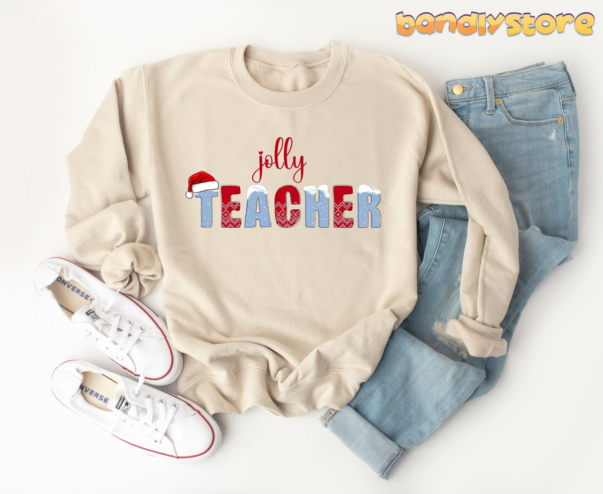 Jolly Teacher Sweatshirt in sand laid flat beside white sneakers and blue jeans on a white surface.