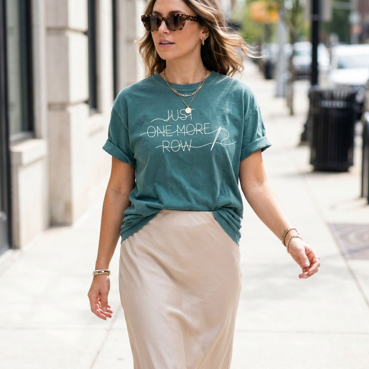 Just One More Row T-Shirt in Blue Spruce on a woman walking a city sidewalk by buildings and cars.