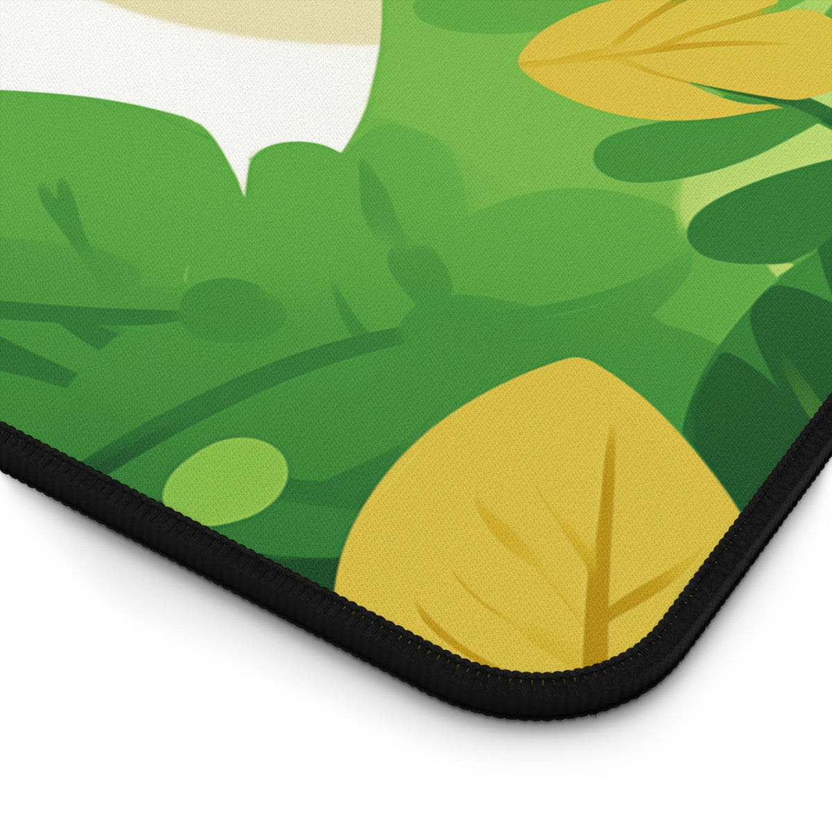 Cute Kawaii Cat Desk Mat close-up corner angle on white showing green yellow leaf print and black stitched edge.