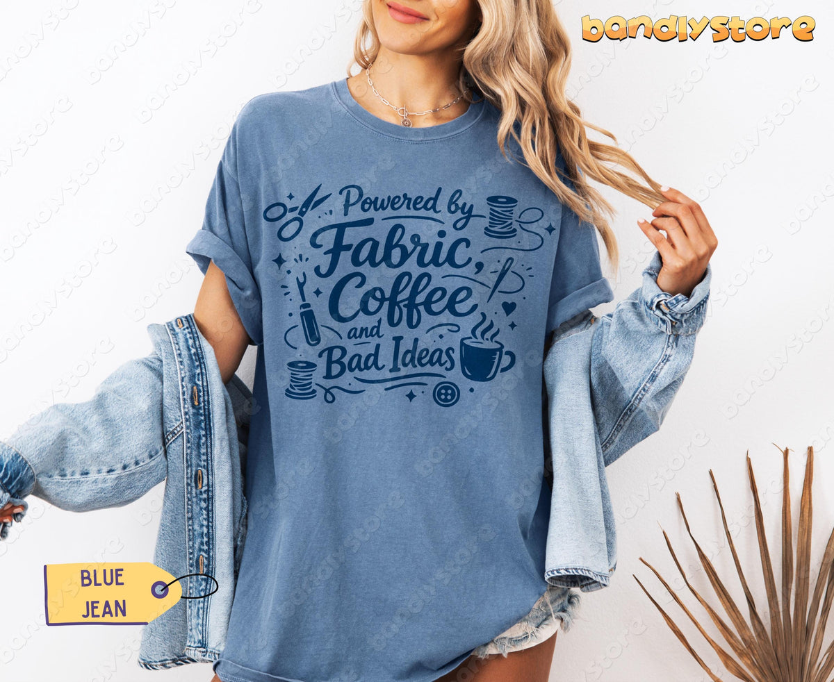 Linocut Sewing T-Shirt in Blue Jean on a model holding a denim jacket, front view by a wall with plant.