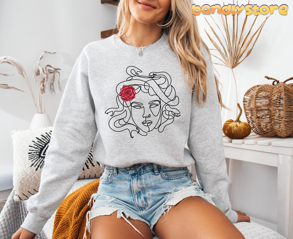 Medusa Sweatshirt in ash on a seated woman amid dried plants, pumpkins and wicker baskets.