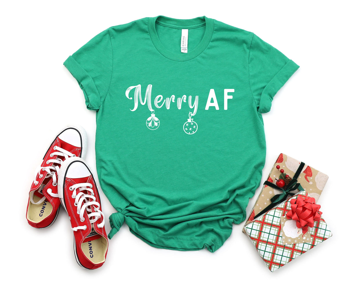 Merry AF T-Shirt in Heather Kelly laid flat from above with red sneakers and wrapped gifts.