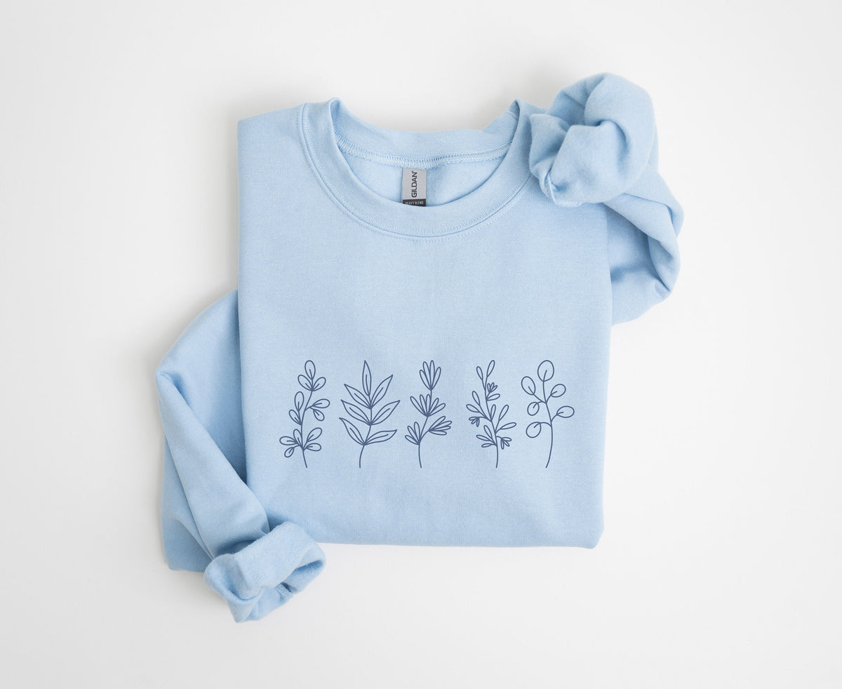 Monochrome Floral Sweatshirt light blue folded flat on plain white surface showing dark floral line drawings.