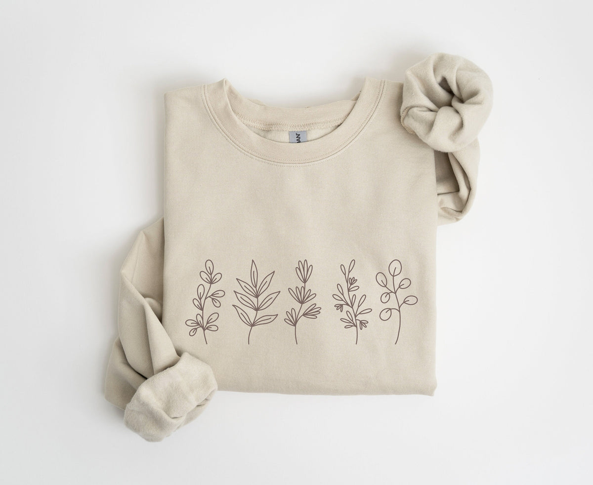 Monochrome Floral Sweatshirt in sand, folded flat on white with sleeves rolled, five line-drawn plants across the front.