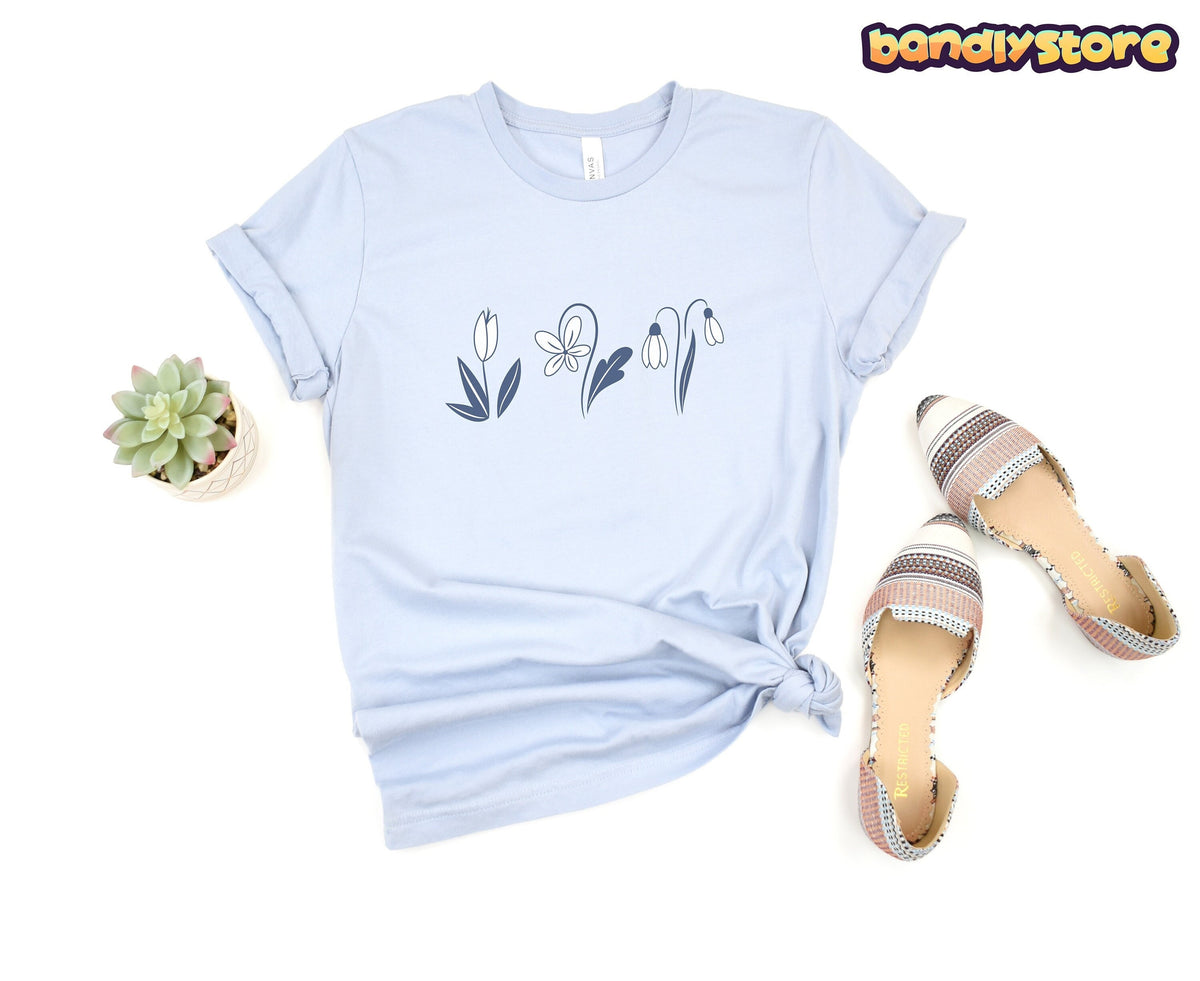 Monochromatic Spring Flowers T-Shirt in light blue shown top-down on white with succulent and striped flats.