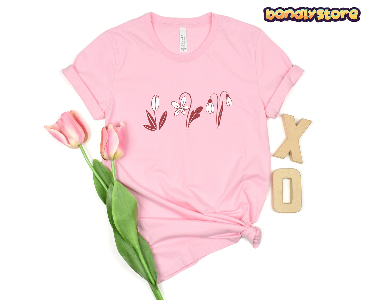 Monochromatic Spring Flowers T-Shirt in pink laid flat on white with tulips and wooden X and O letters.