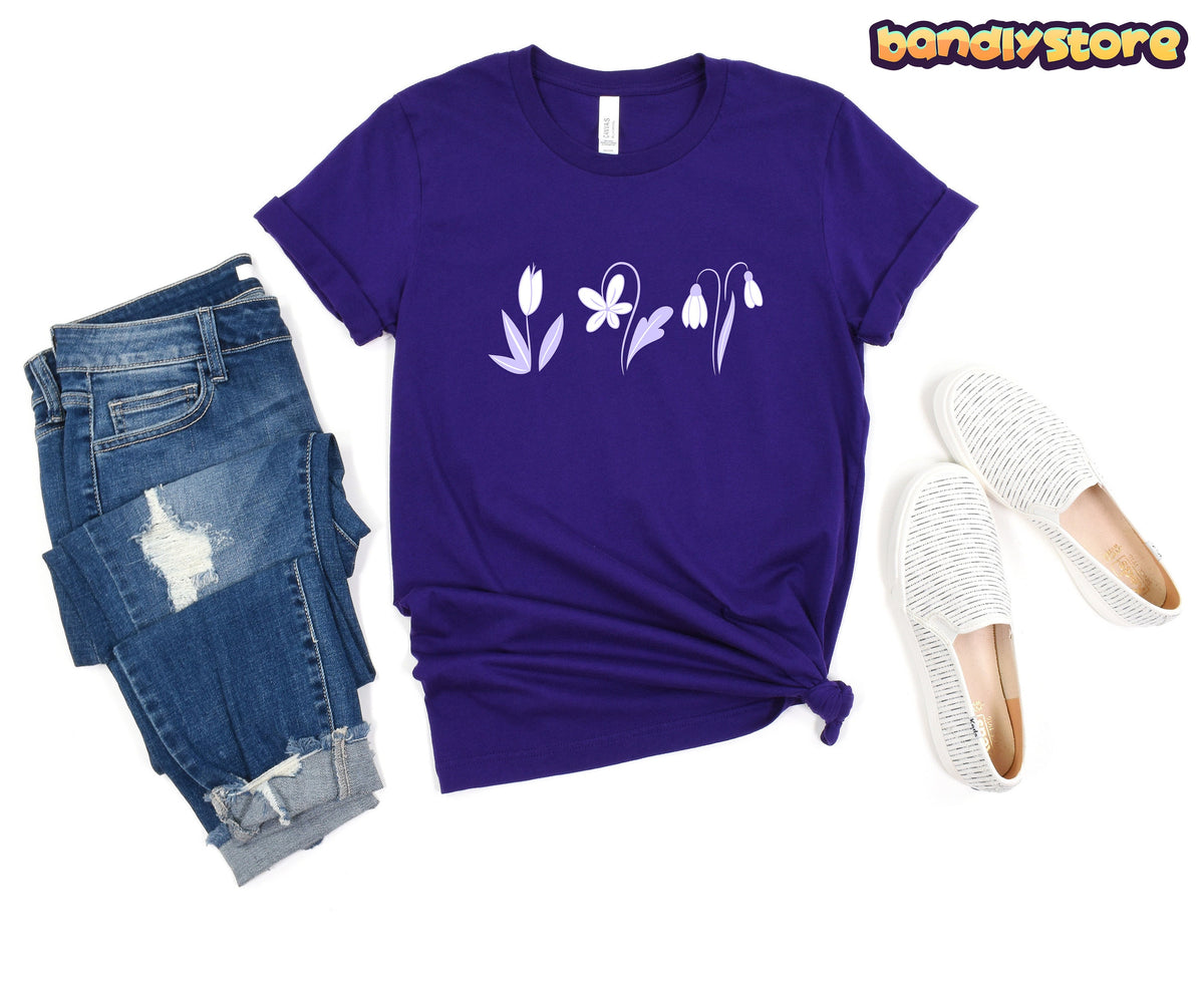 Monochromatic Spring Flowers T-Shirt in Team Purple flat-laid from above beside jeans and slip-on shoes.