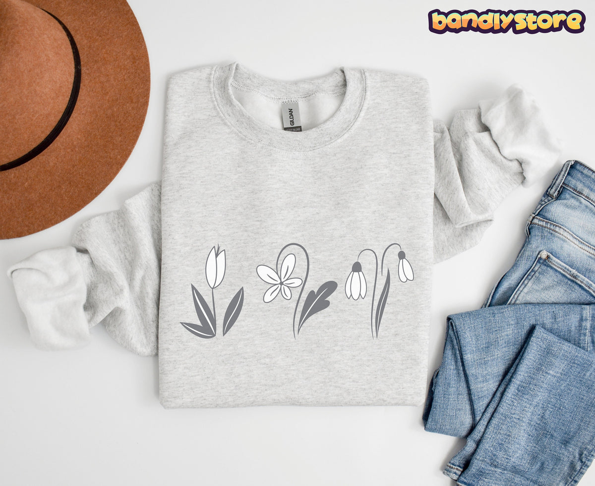 Monochrome Spring Flowers Sweatshirt in ash, folded flat beside a brown hat and blue jeans on white.