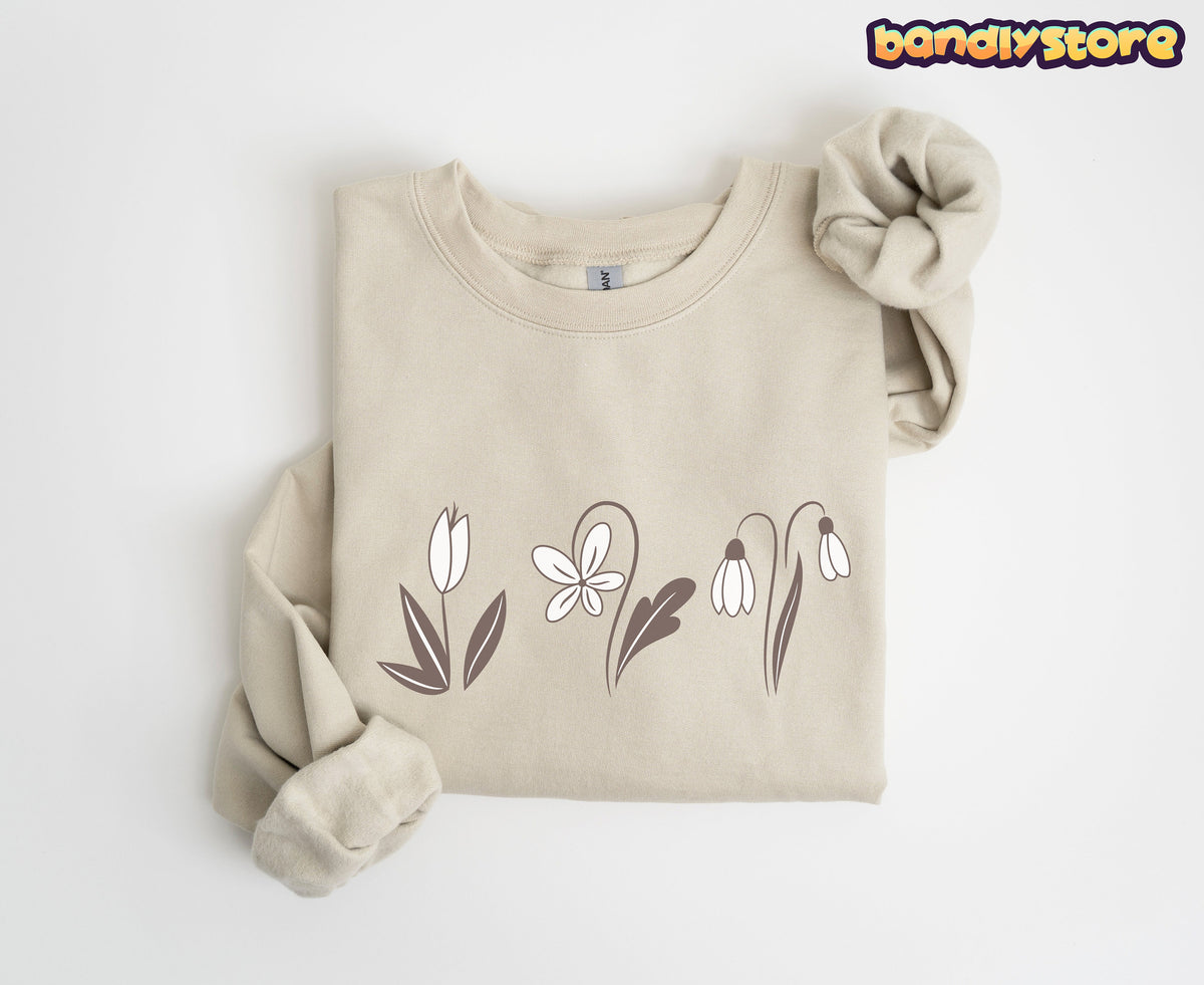 Monochrome Spring Flowers Sweatshirt folded flat in sand on white, sleeves rolled, simple brown-and-white flower line art across the chest.