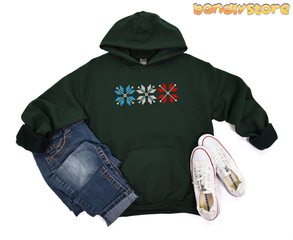 Old Fashioned Snowflake Hoodie in forest green, flat-laid with folded jeans and white sneakers.