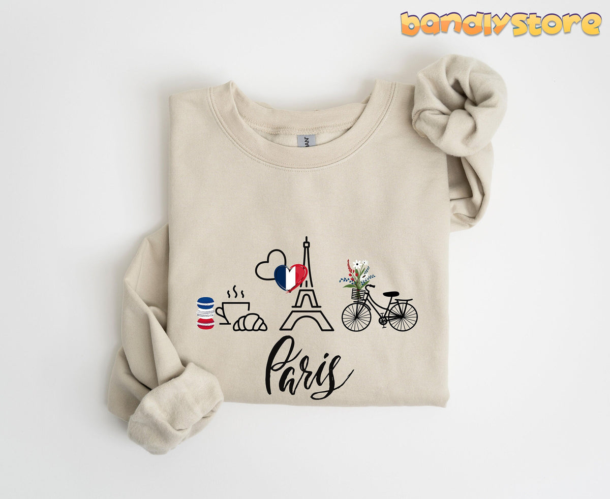 Paris Eiffel Tower Sweatshirt in sand folded flat on white with Eiffel Tower, bike, pastries and Paris script.