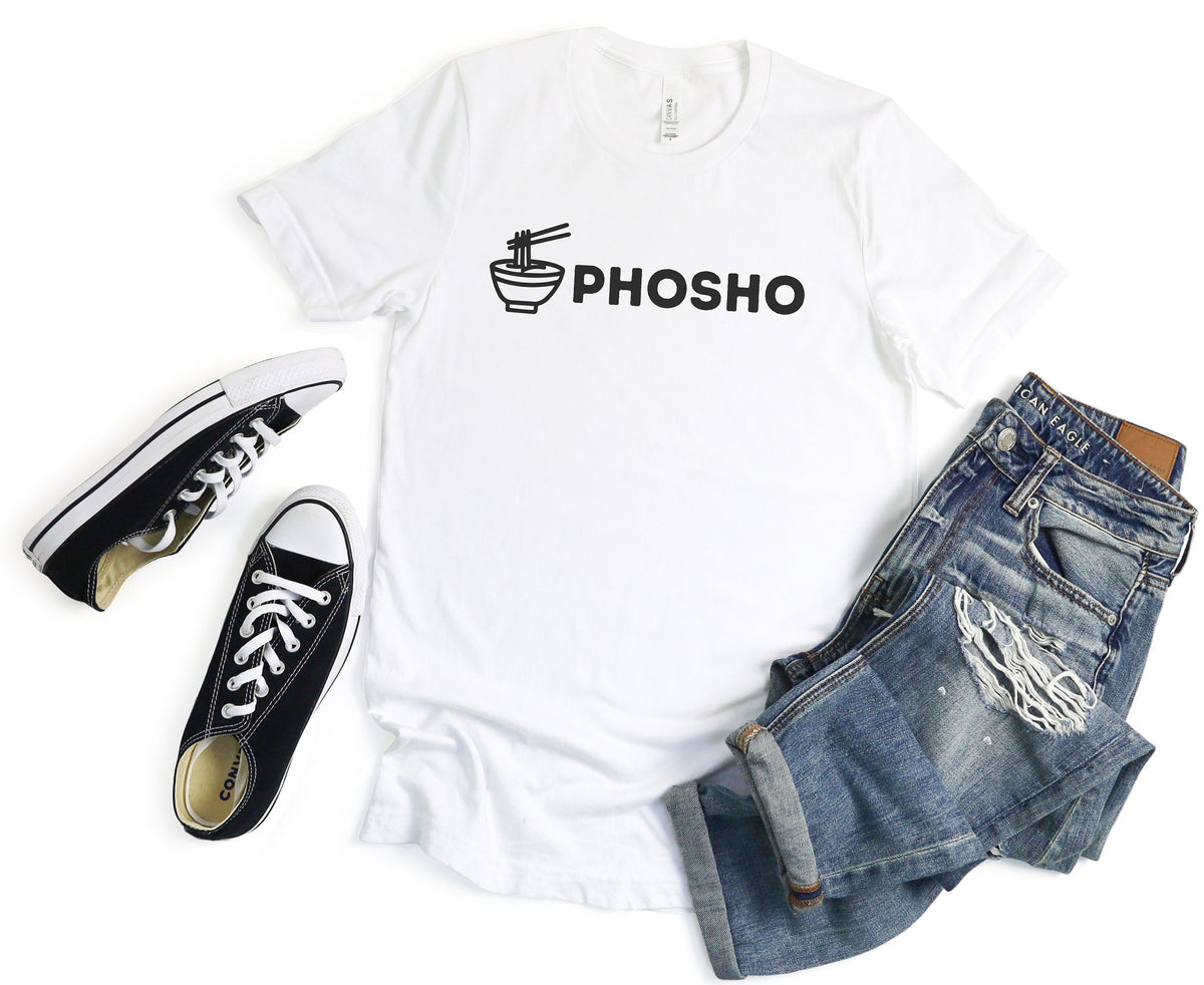 Pho Sho T-Shirt in white, flat-laid with black sneakers left and rolled ripped blue jeans right.