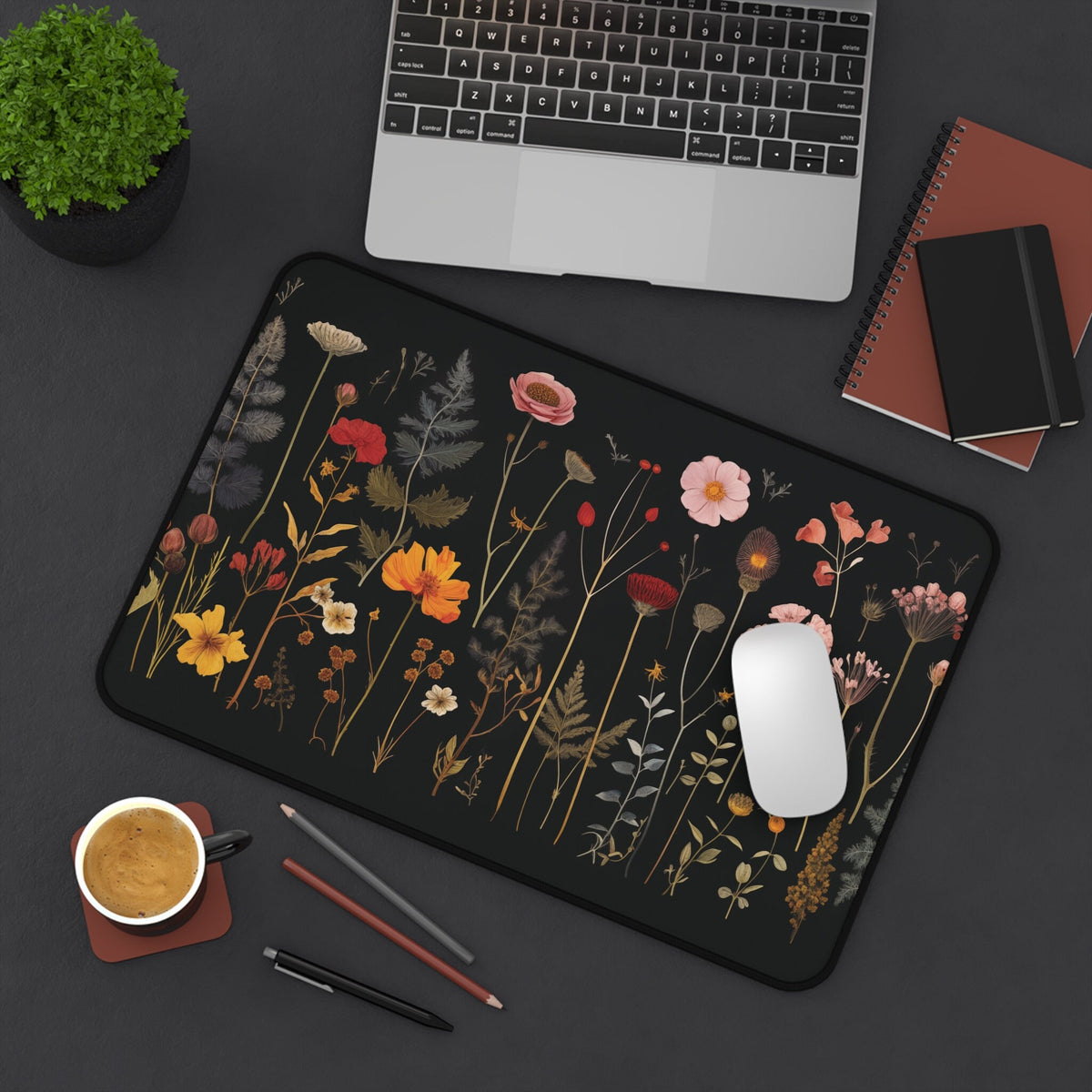 Pressed Wildflowers Desk Mat in 12 × 18 inches overhead on dark desk next to laptop, plant, coffee, pens and mouse.