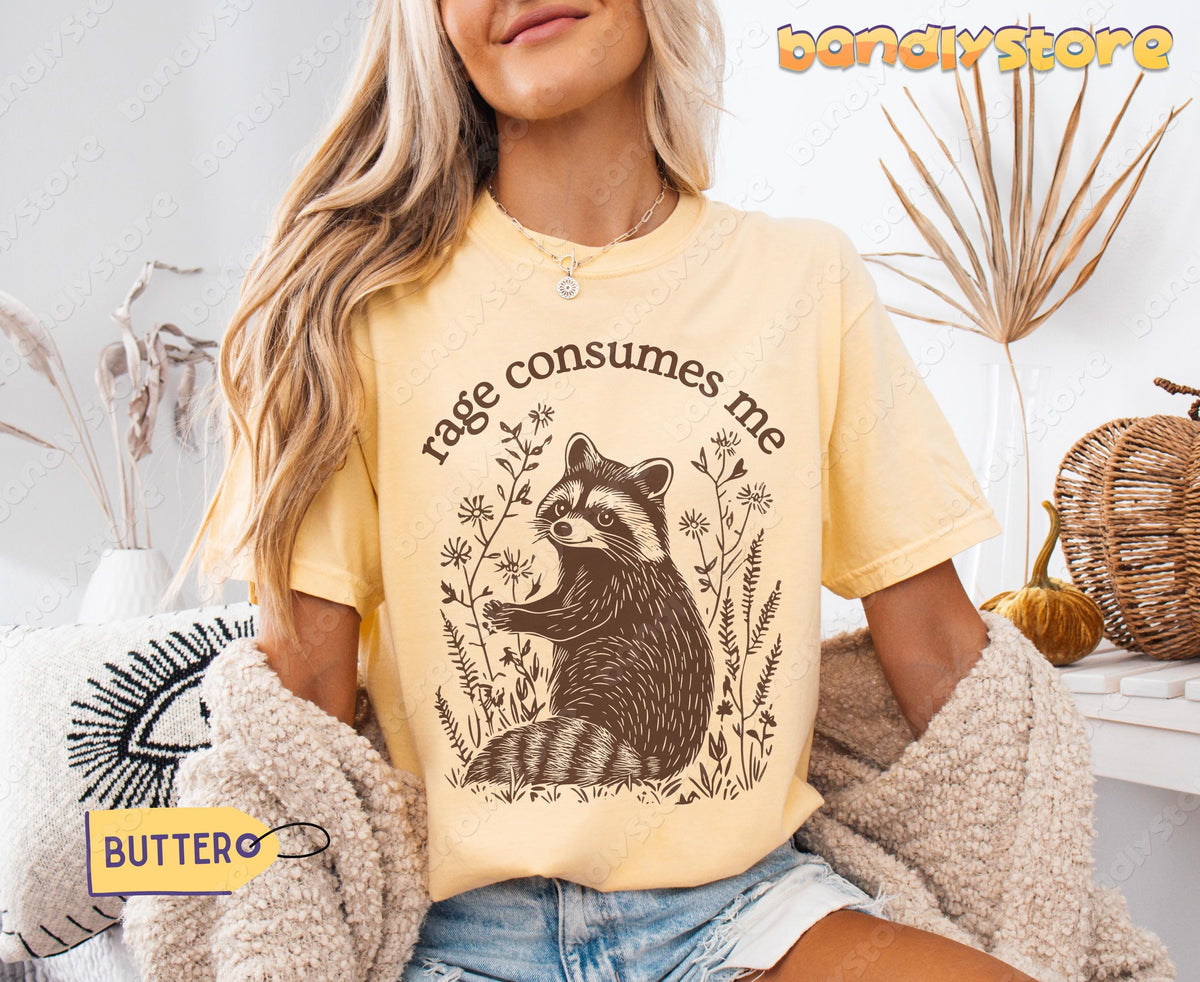 Rage Consumes Me T-Shirt in butter on a seated model with dried plants, pumpkins and basket nearby.