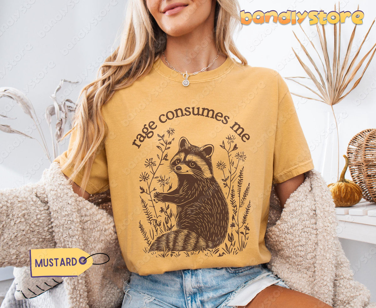 Rage Consumes Me T-Shirt in mustard on a seated model indoors beside dried plants and a pumpkin.