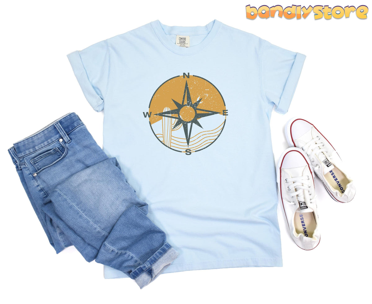 Retro Compass T-Shirt in chambray laid flat beside jeans and sneakers.