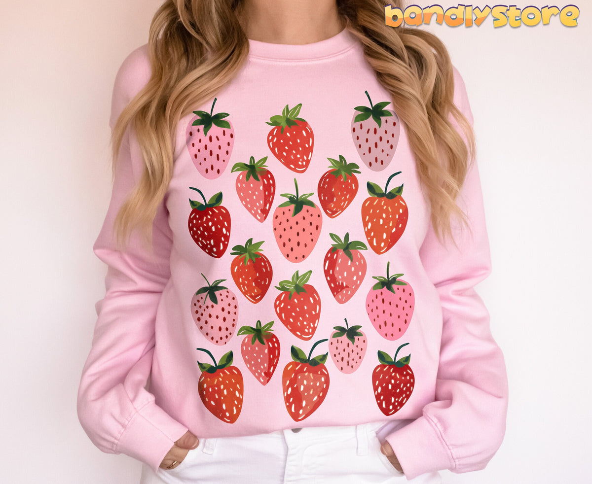 Retro Strawberry Sweatshirt on a light pink sweatshirt worn by a person standing front-facing against a plain wall.