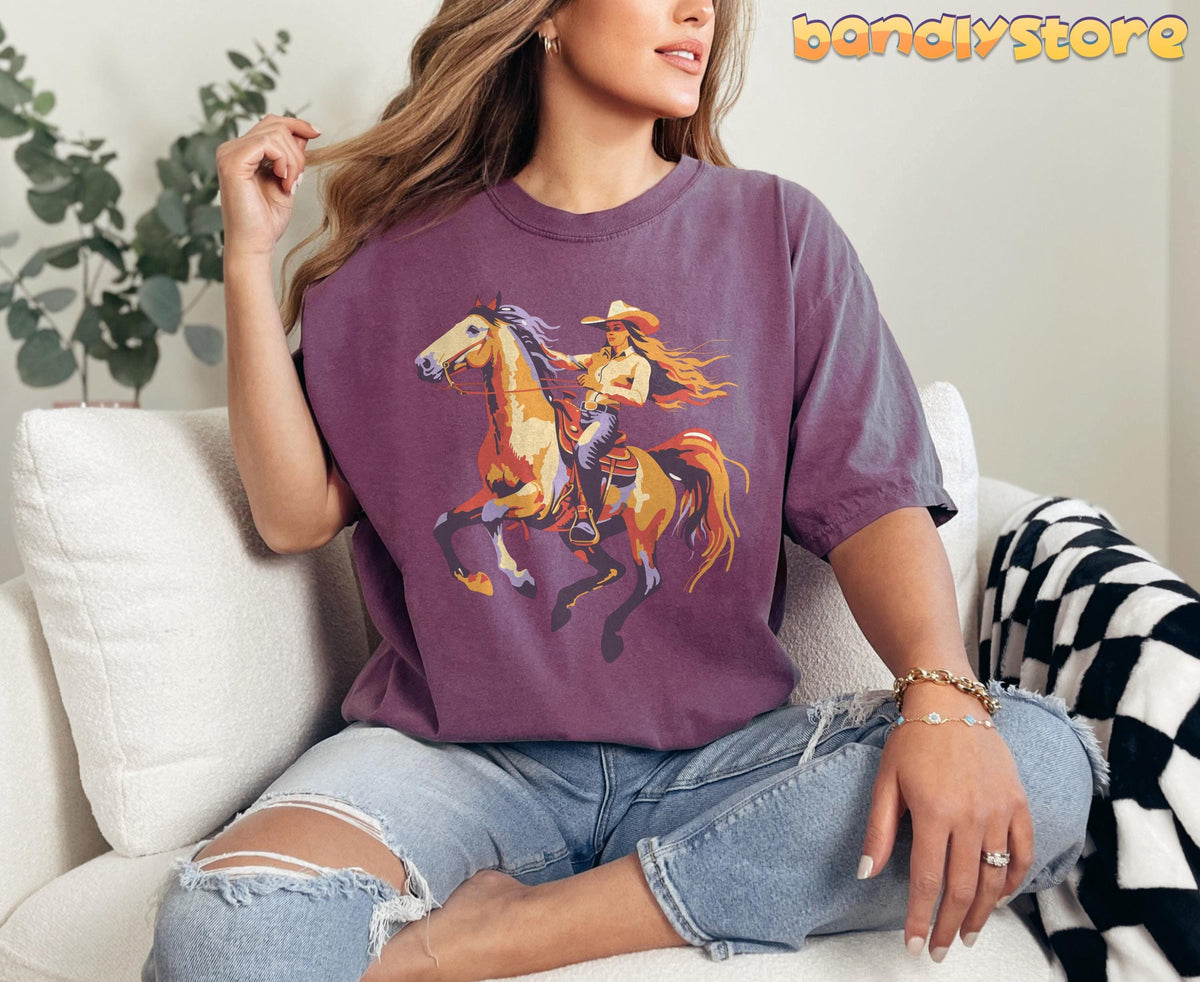 Retro Yeehaw Cowgirl T-Shirt in Berry, worn by a seated woman on a white sofa with plants nearby.