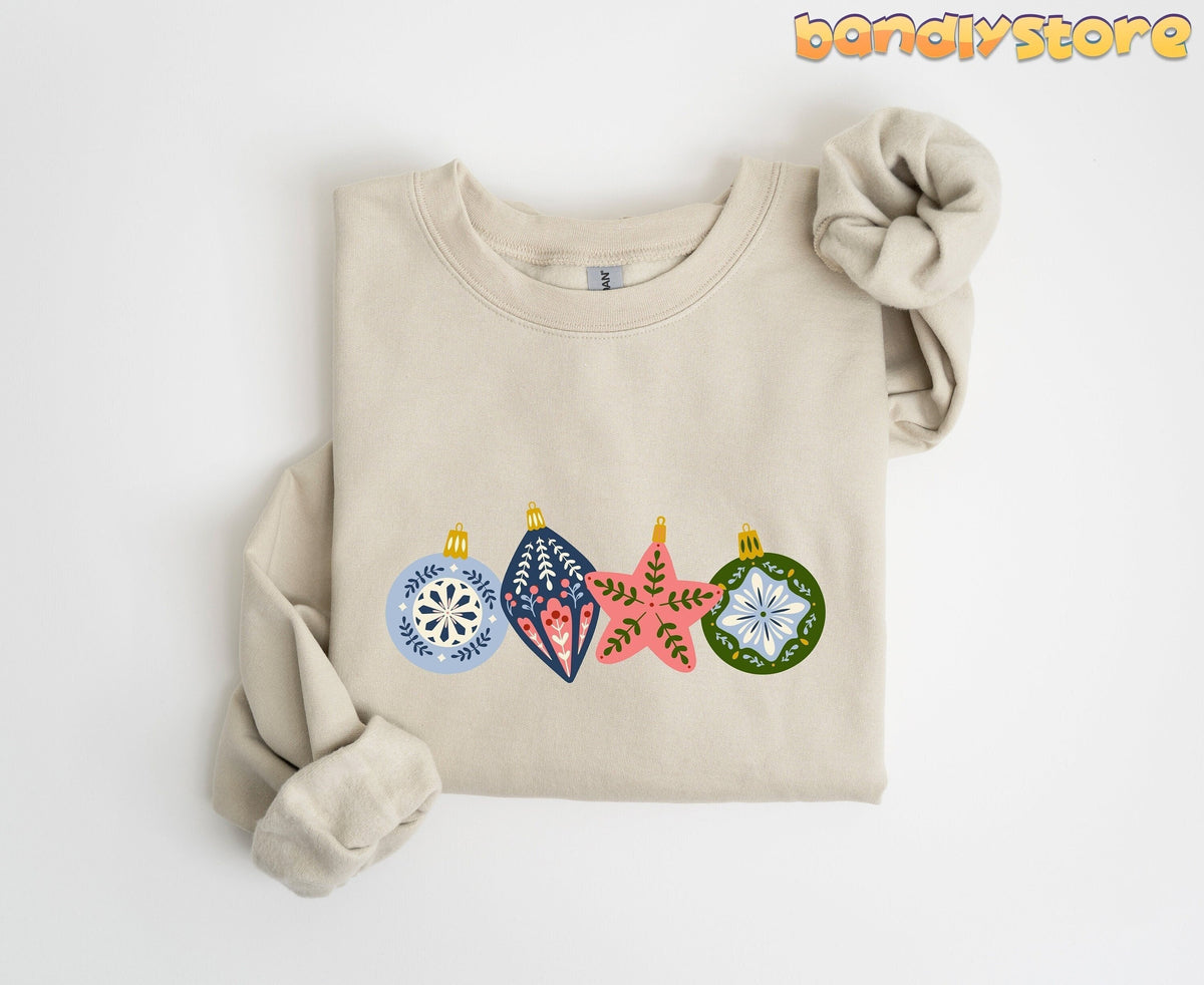 Scandinavian Christmas Sweatshirt in sand, folded flat on white with four folk-style ornaments across the chest.