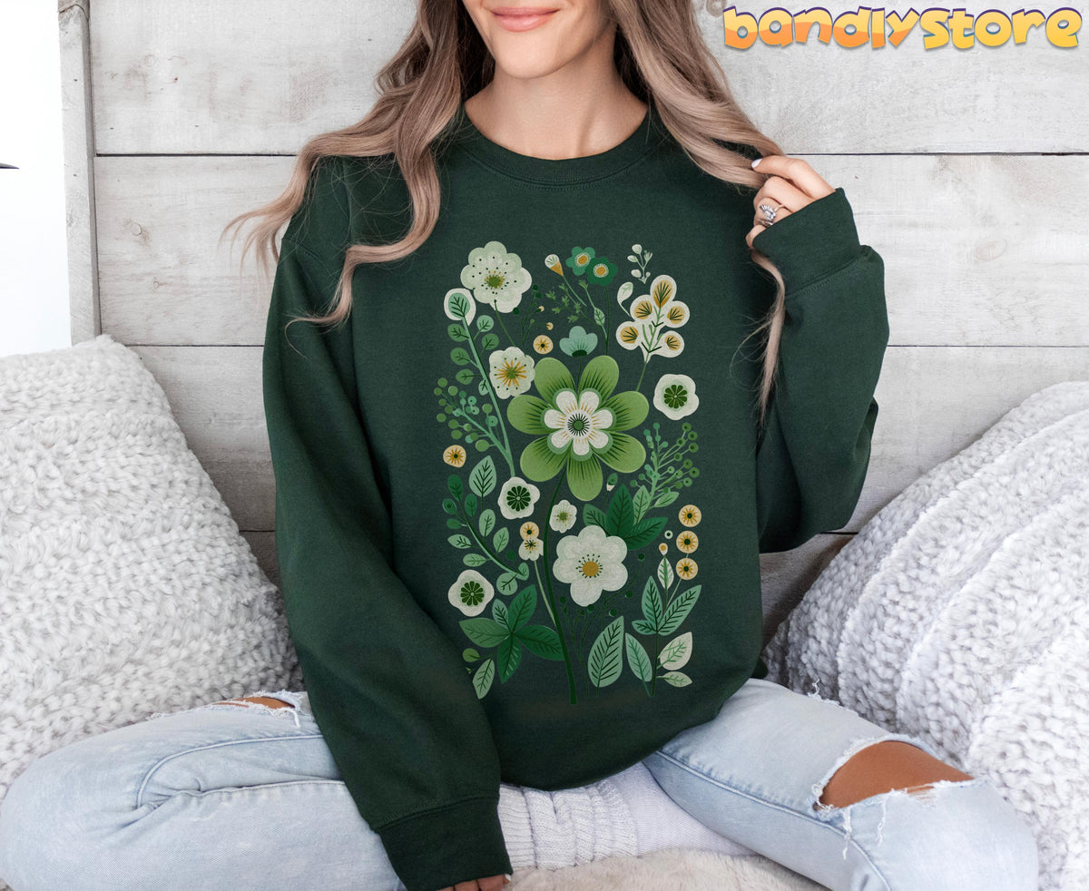 Scandinavian Wildflowers Sweatshirt in forest green on a woman sitting cross-legged against a wooden wall with white pillows.