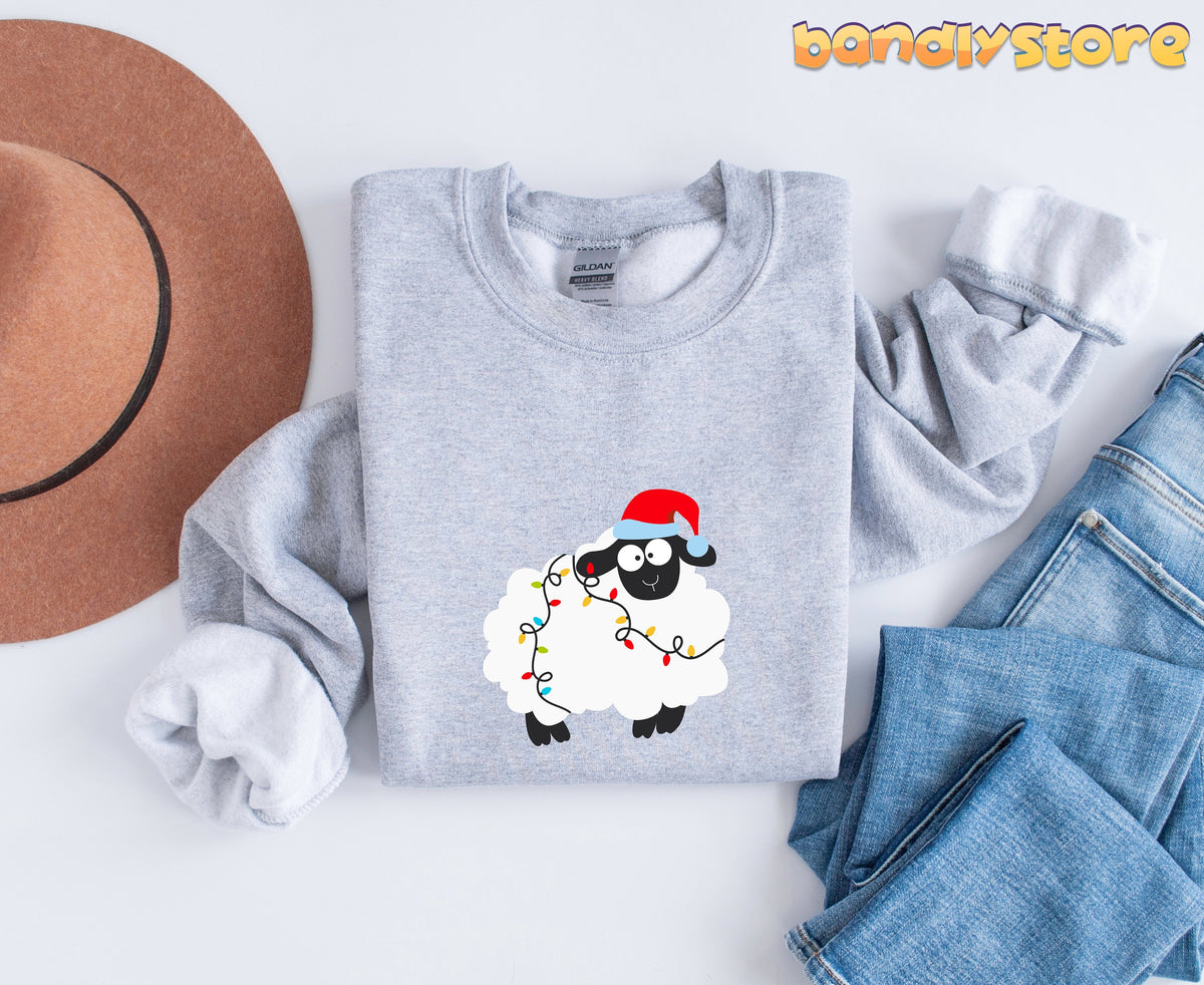 Sheep Christmas Lights Sweatshirt in Sport Grey folded flat beside a brown hat and blue jeans.