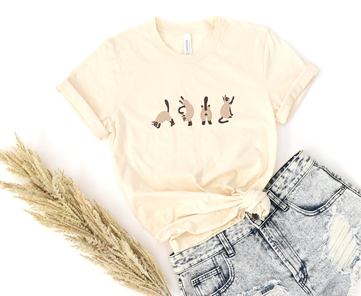 Siamese Cat T-Shirt in natural laid flat with cat prints, dried grass left and ripped jeans below.