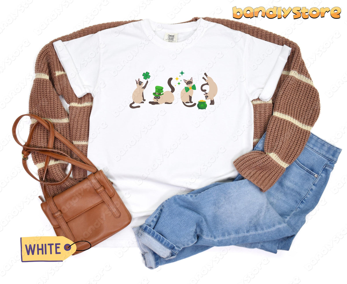 Siamese Cat Shamrock T-Shirt in white flat-laid with brown sweater, blue jeans and brown bag.