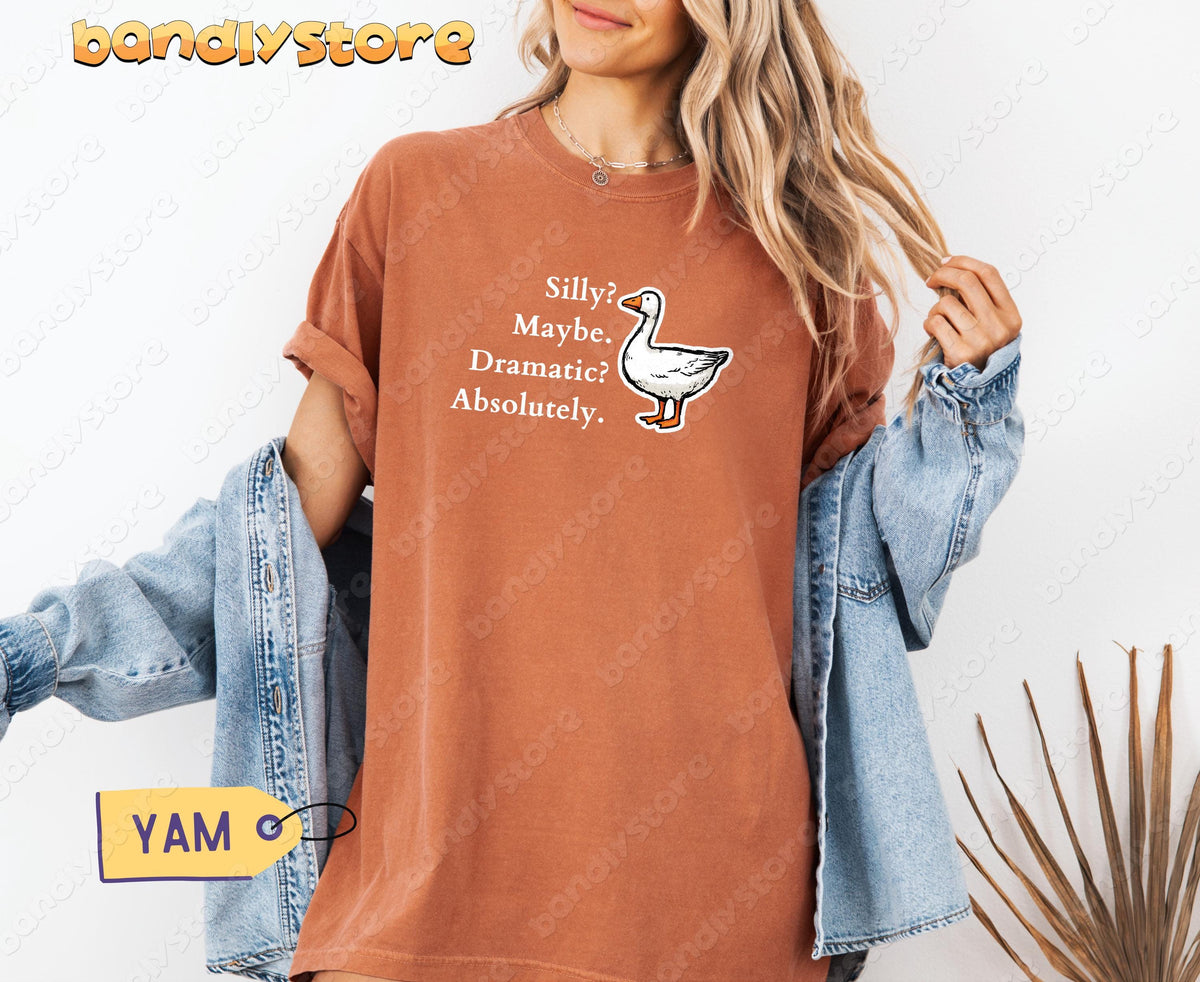 Silly Goose T-Shirt in Yam on model facing forward, denim jacket off shoulders, white wall and dried fronds nearby.