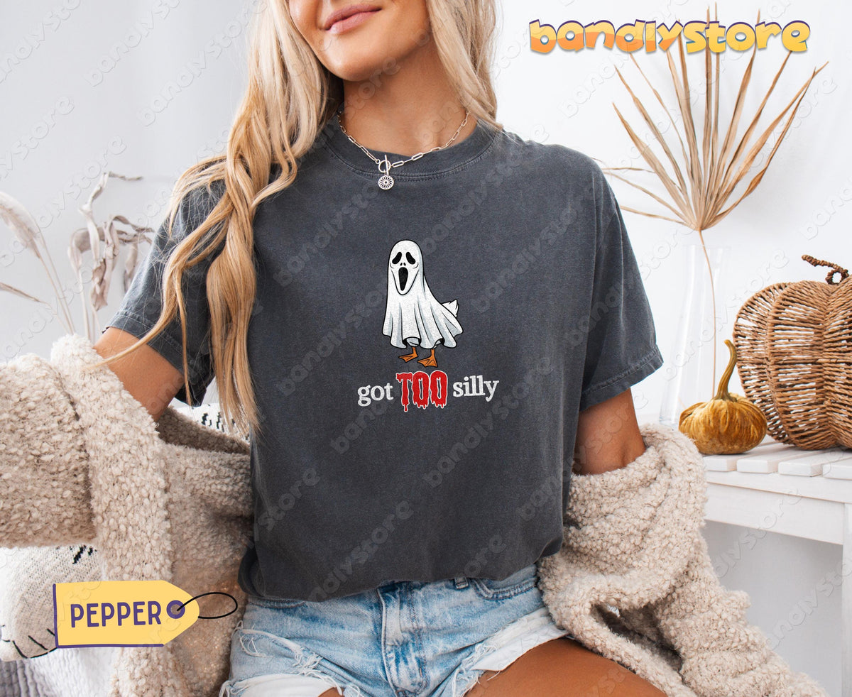 Silly Goose T-Shirt in Pepper on a seated woman, front view, beside dried plants and a pumpkin.