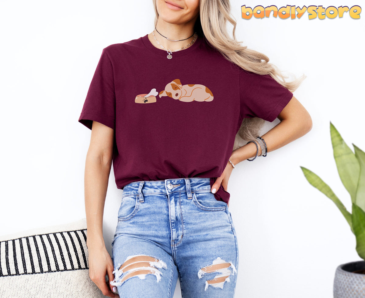Sleeping Dog T-Shirt in maroon on a woman facing forward indoors by a plant and striped cushion.