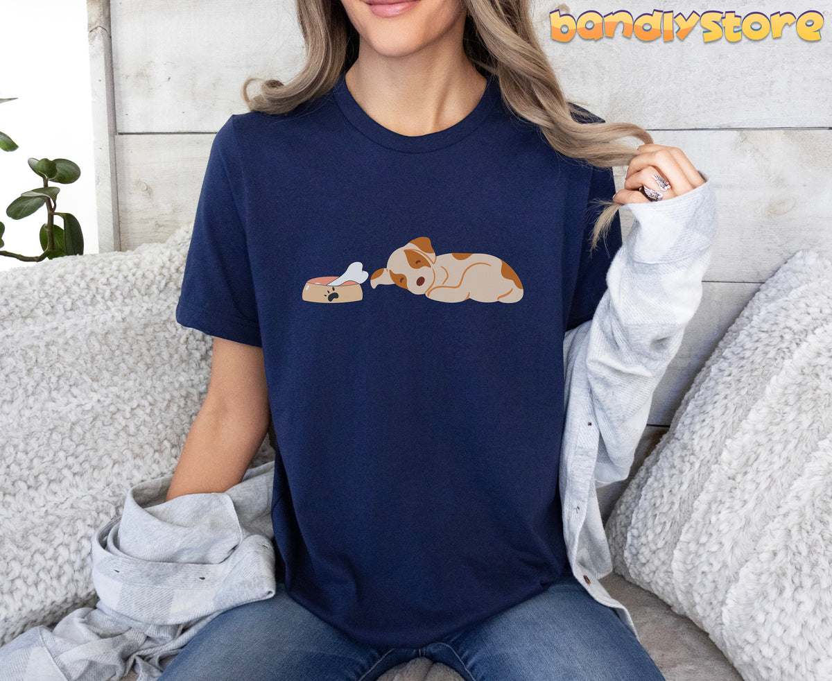 Sleeping Dog T-Shirt in navy on a seated model amid couch pillows against a wood wall.