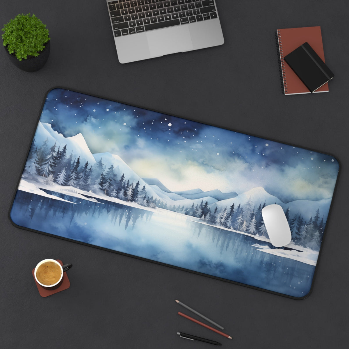 Snow Mountains Desk Mat 16 × 32 inches displayed top-down on a desk with laptop, plant, coffee, notebooks, pens and mouse.