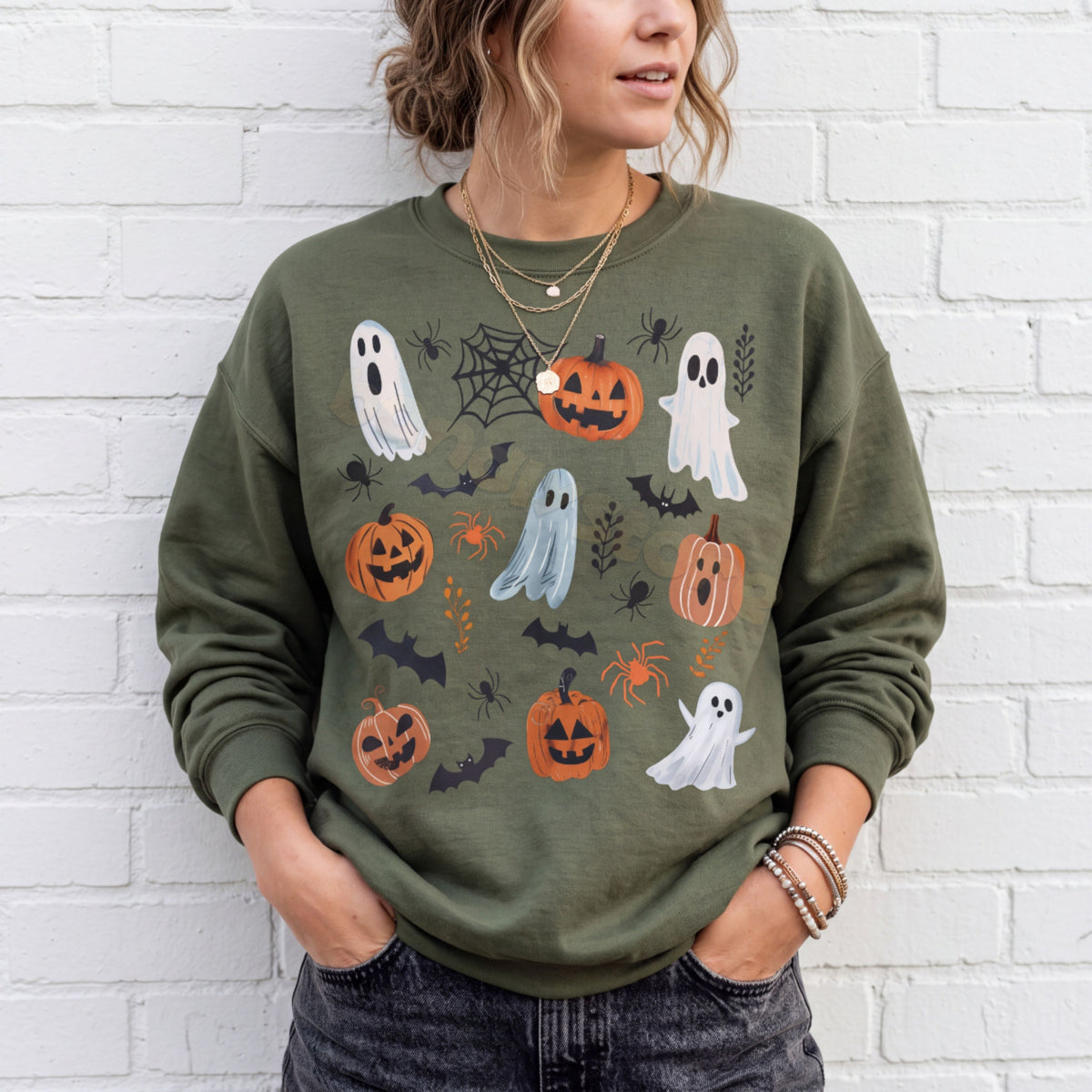 Spooky Ghosts And Pumpkins Sweatshirt in military green, front view on a person against a white brick wall.